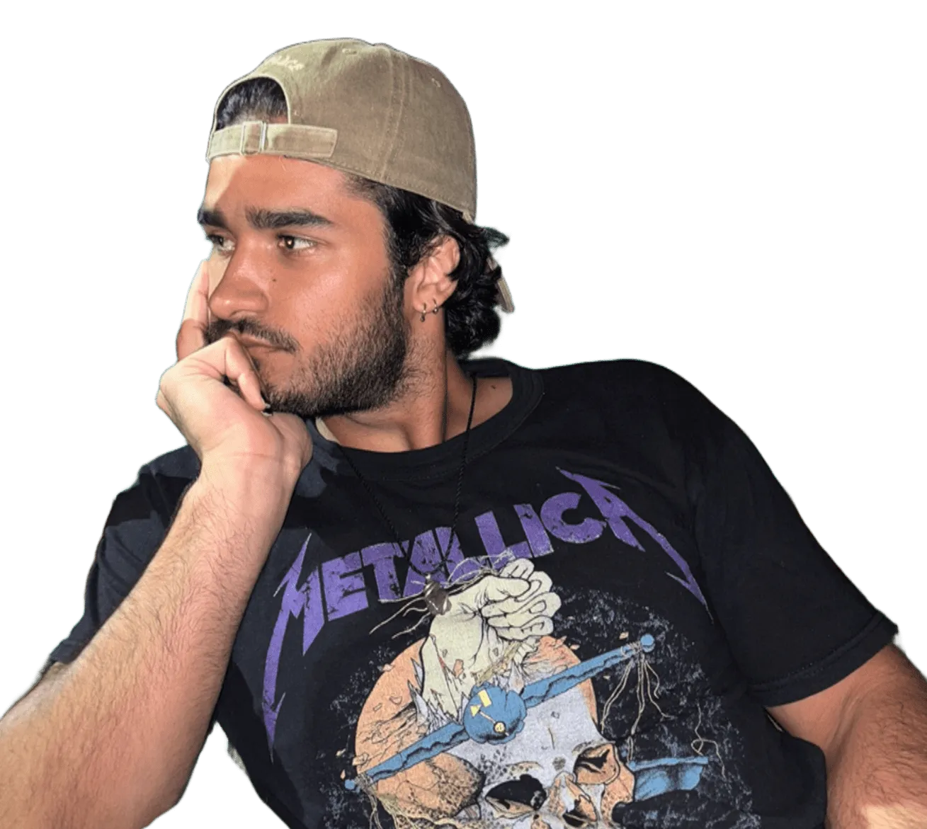 Bruno in a cap and a Metallica shirt, chin on his hand, looking away